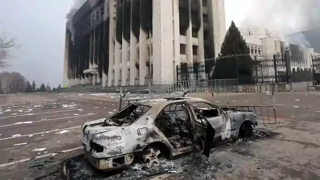 Kiégett egy autó a polgármesteri hivatal épülete előtt, amelyet felgyújtottak az almati tüntetések során. Fénykép: Pavel Mikheyev/Reuters
